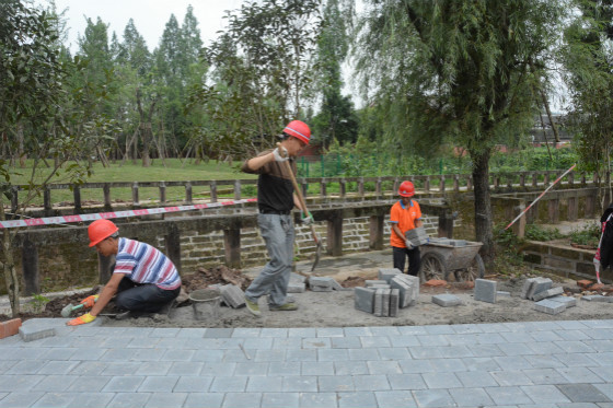 梁平区金带镇生态停车场施工现场,工人们正在砌水沟,铺设透水砖.